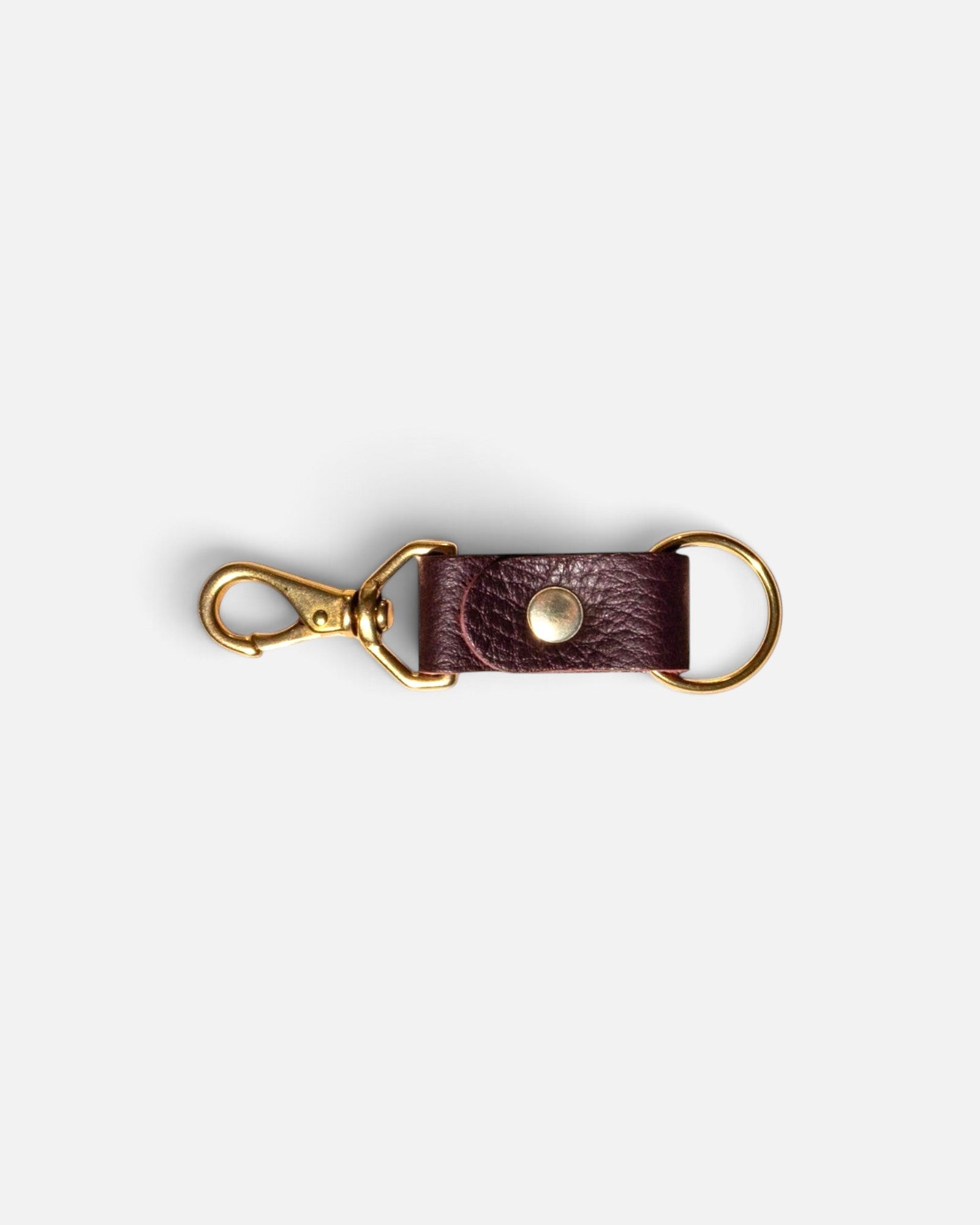JONES + CO plum leather keychain with gold-toned metal clasp and ring on a light grey background.