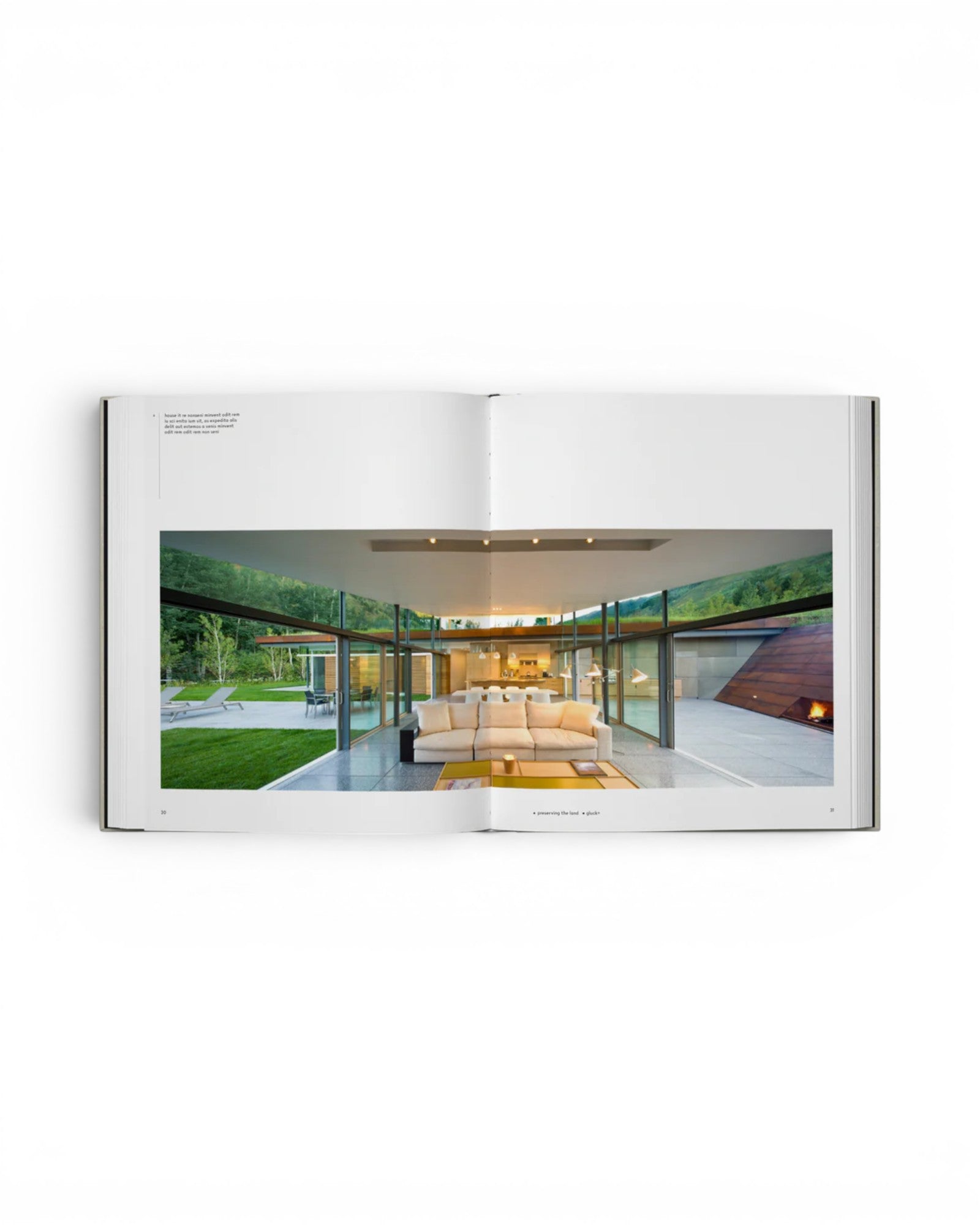 JONES + CO Private Aspen book open to a spread showing a modern mountain home with glass walls and a white sofa.