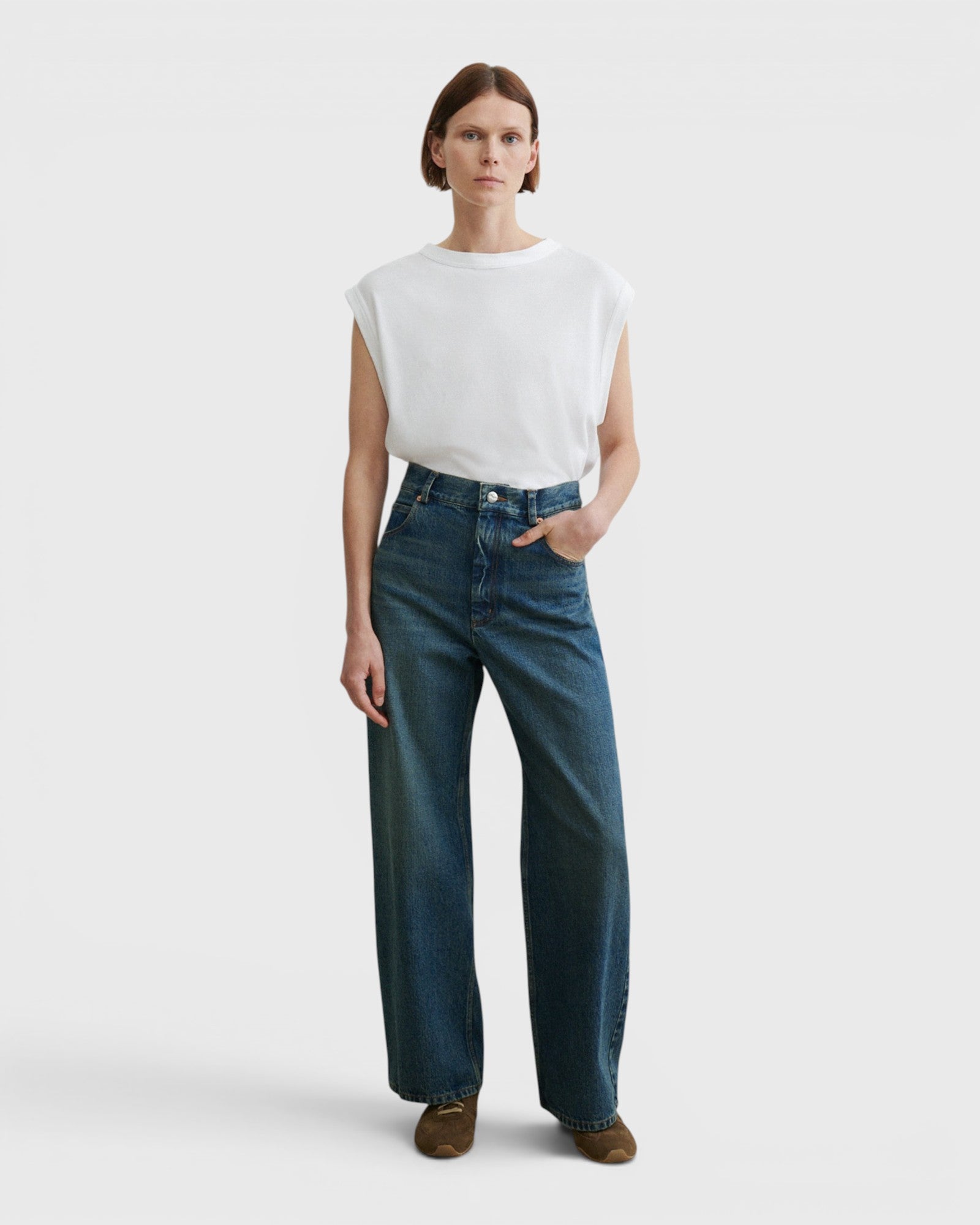 JONES + CO Puerto Pant in aged indigo cotton denim, a high-rise straight-leg jean worn by a model.