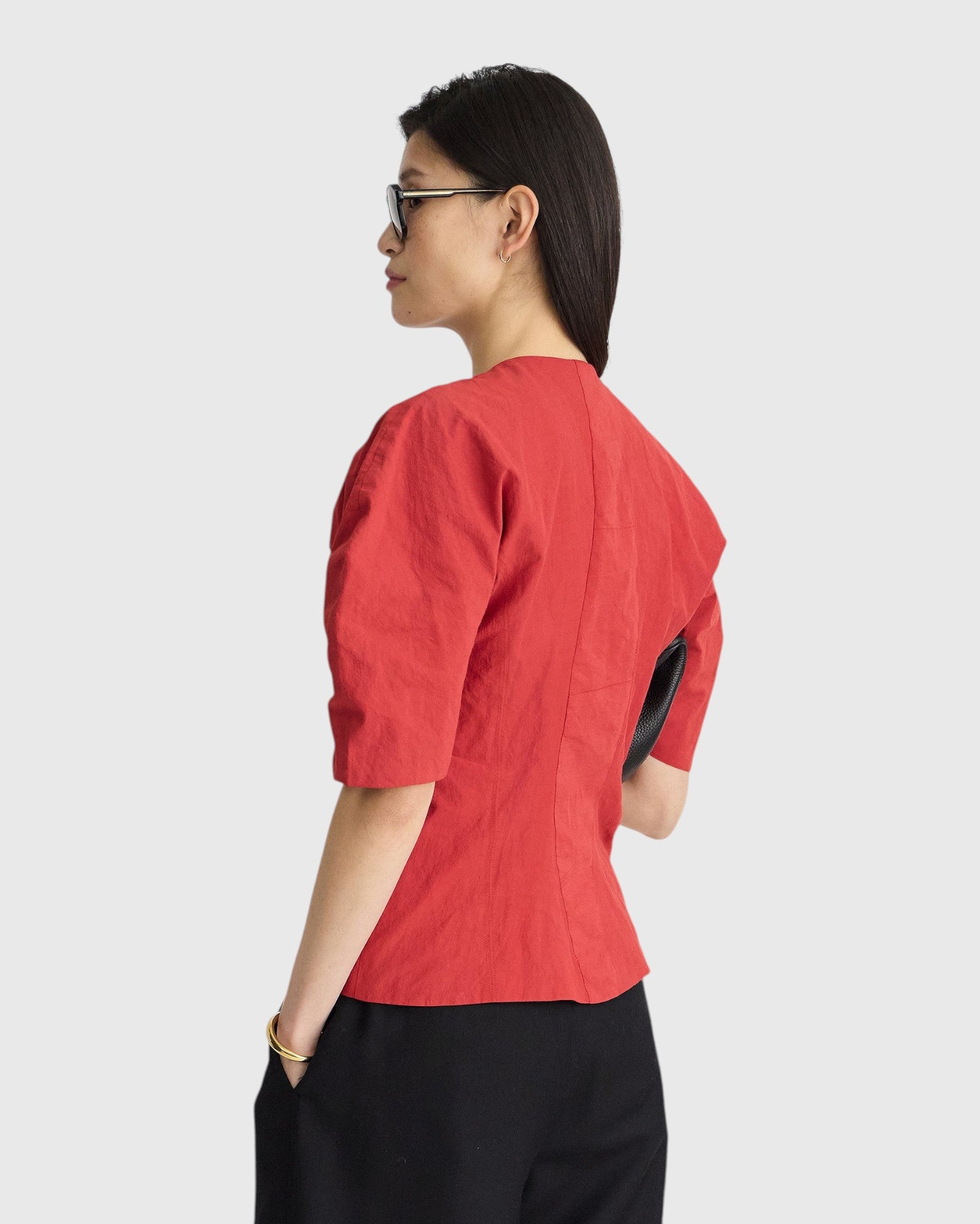 JONES + CO red crew-neck top with short puff sleeves and metallic thread detail worn by a model in profile view