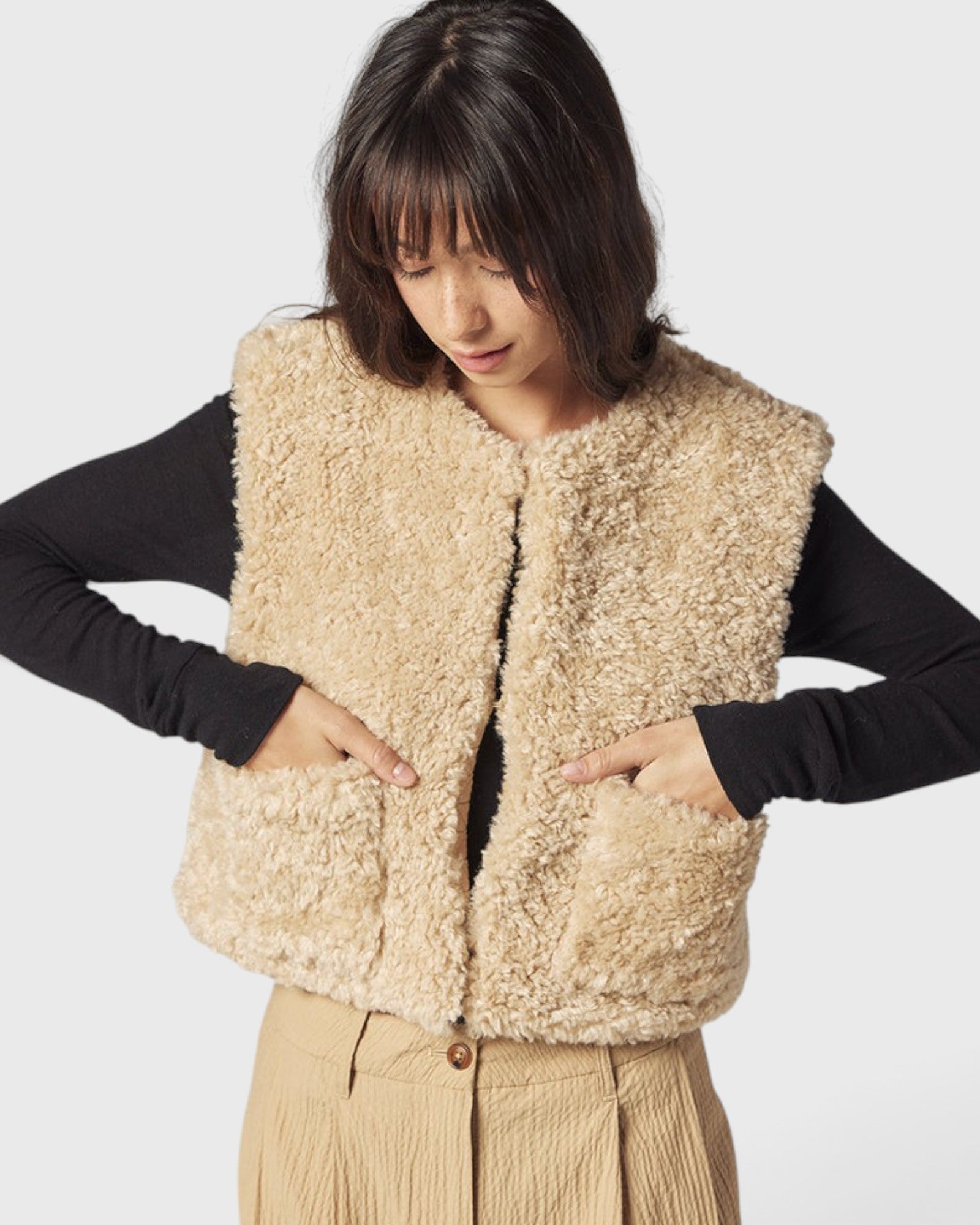 JONES + CO reversible short vest in oatmeal faux fur with a collarless design and front patch pockets