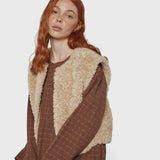 JONES + CO reversible short vest in oatmeal faux fur worn over a brown plaid dress by a red-haired model