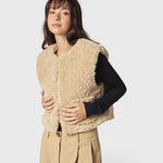 JONES + CO reversible short vest in oatmeal faux fur worn by a model over a black long-sleeve top