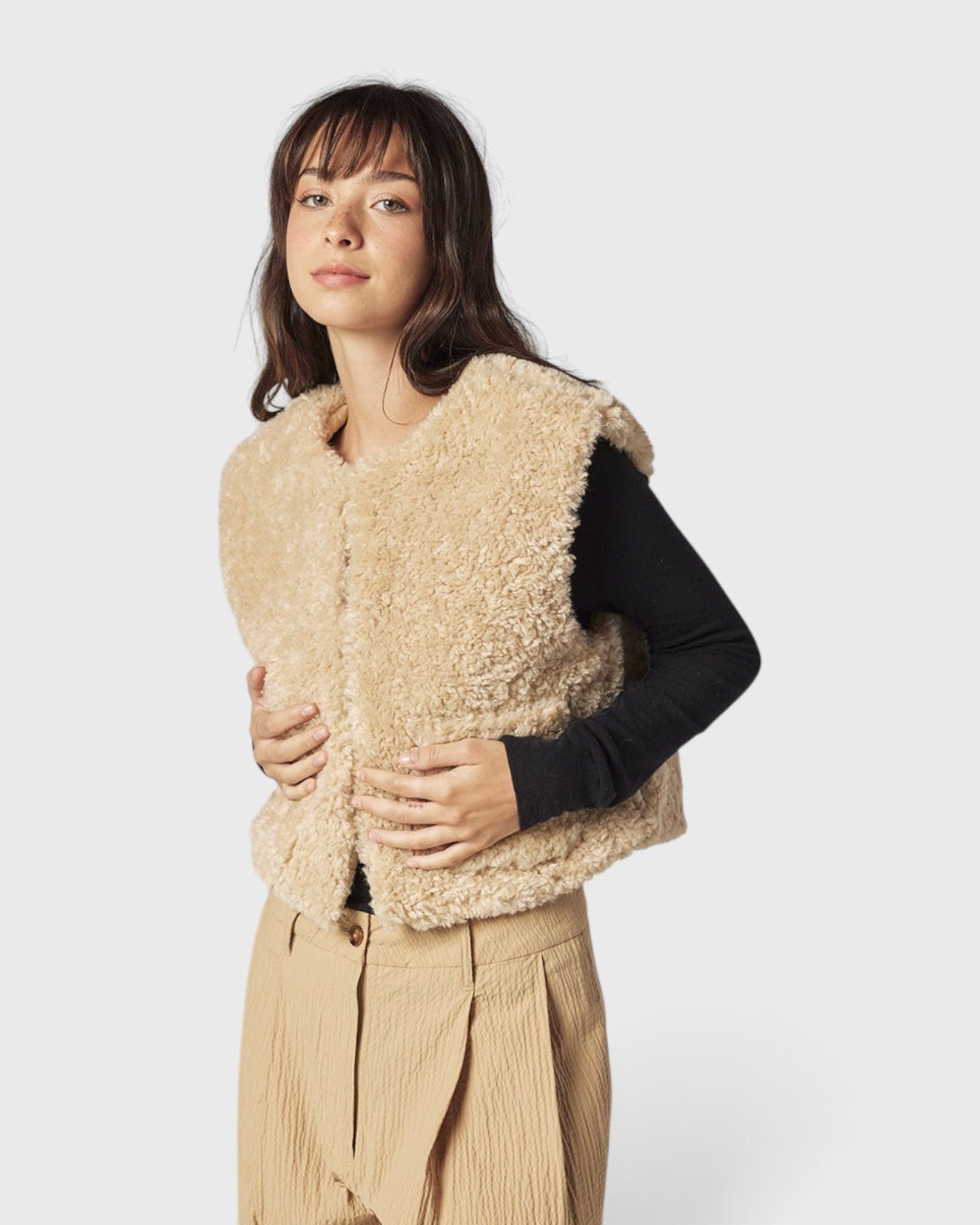 JONES + CO reversible short vest in oatmeal faux fur worn by a model over a black long-sleeve top