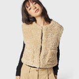 JONES + CO reversible short vest in oatmeal faux fur worn by a model over a black long-sleeve top
