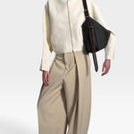 JONES + CO Rider M Elche black leather bag with a hand-braided strap worn crossbody by a model in cream jacket