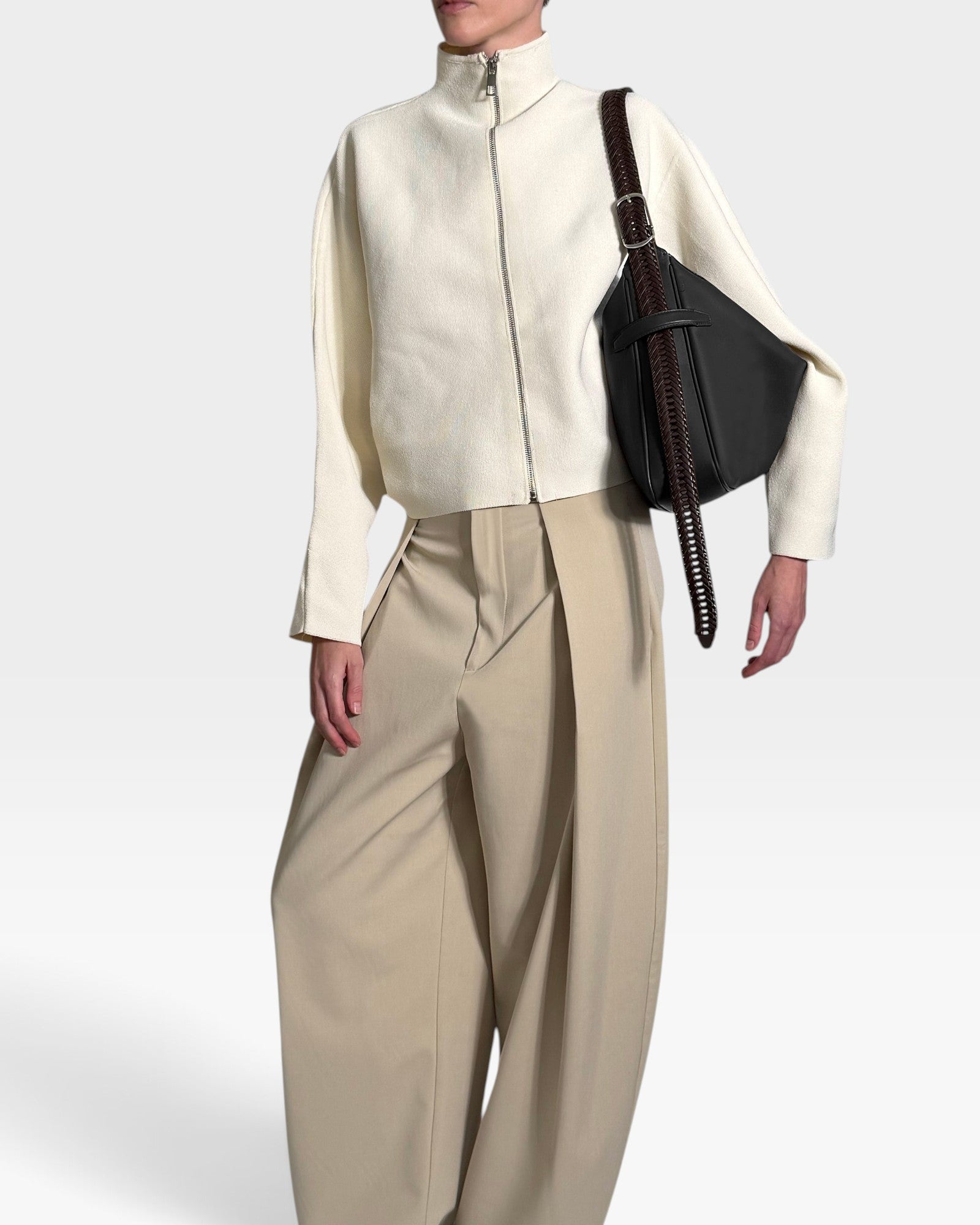 JONES + CO Rider M Elche black leather bag with a hand-braided strap worn crossbody by a model in cream jacket