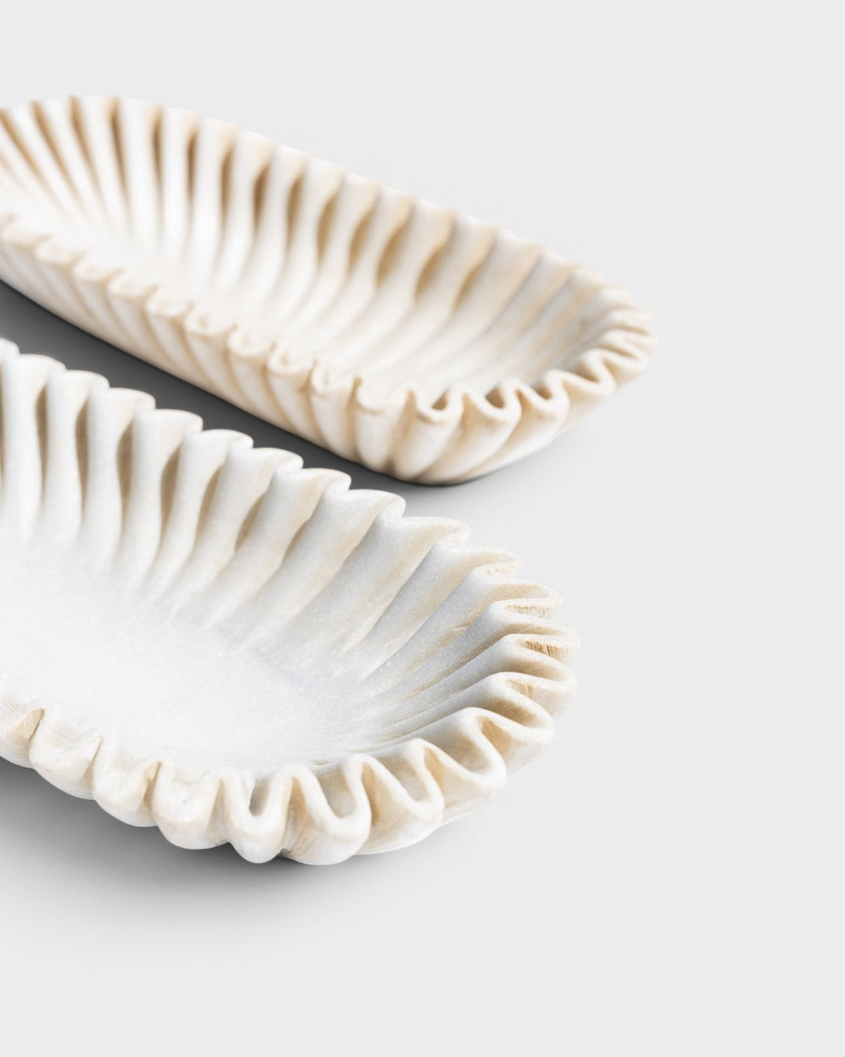 JONES + CO Ruffle Marble Oval Bowl with fluted edges and natural stone veining. Decorative accent.