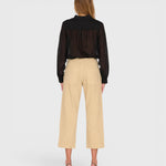 JONES + CO Alex midrise utility cotton jeans in sand with patch pockets, back view on a model wearing a black blouse.