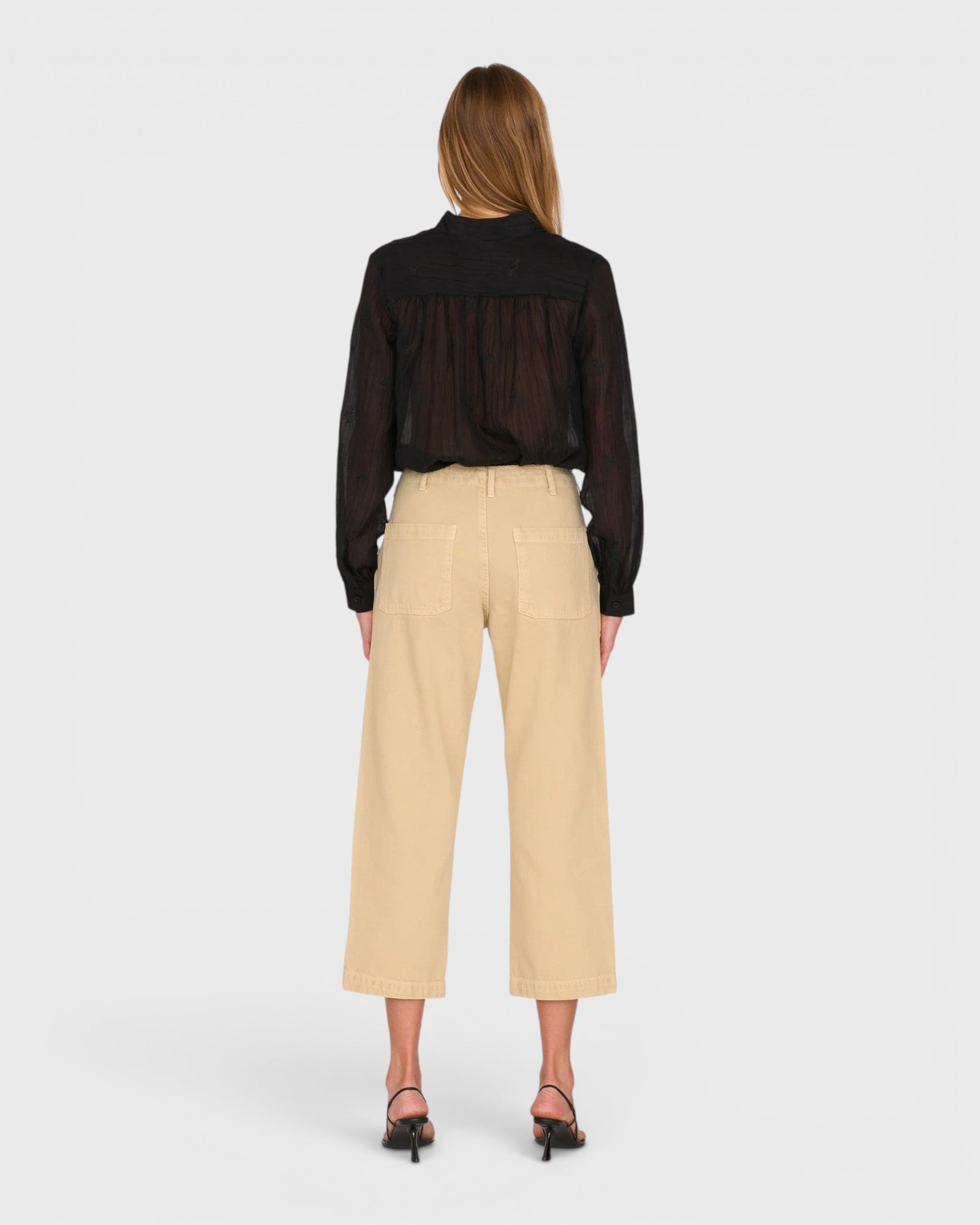 JONES + CO Alex midrise utility cotton jeans in sand with patch pockets, back view on a model wearing a black blouse.