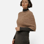 JONES + CO seamless alpaca-blend poncho in dark fawn worn over a charcoal turtleneck sweater by a mature woman.
