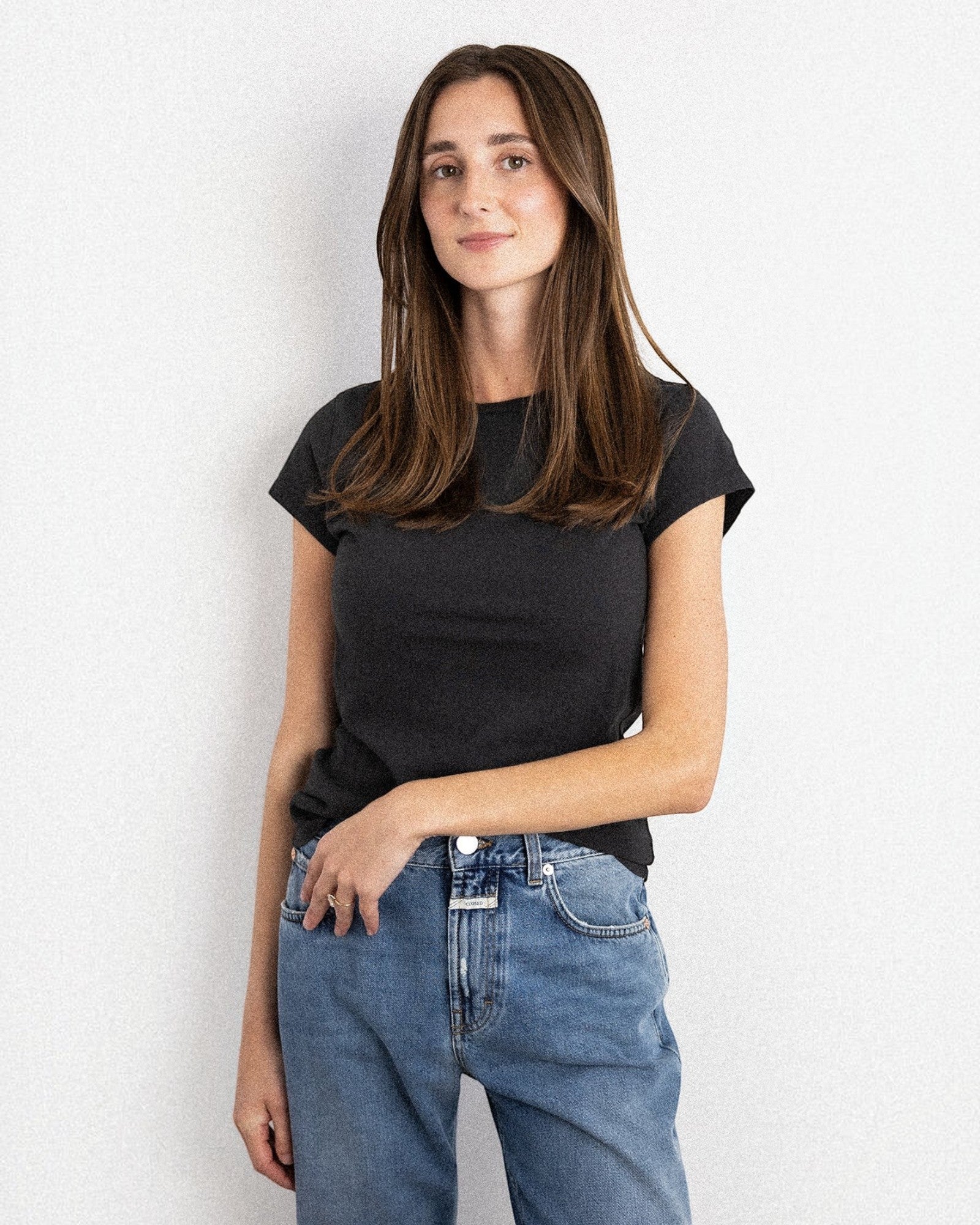 JONES + CO Sheryl baby tee in vintage black recycled organic cotton worn by a woman with blue jeans