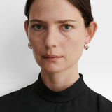 Model wearing JONES + CO silver-plated brass chunky tapered huggie hoop earrings with hinge detail