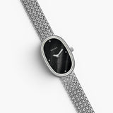 JONES + CO Jane Small watch with a silver woven mesh bracelet and a black oval dial on a white background.