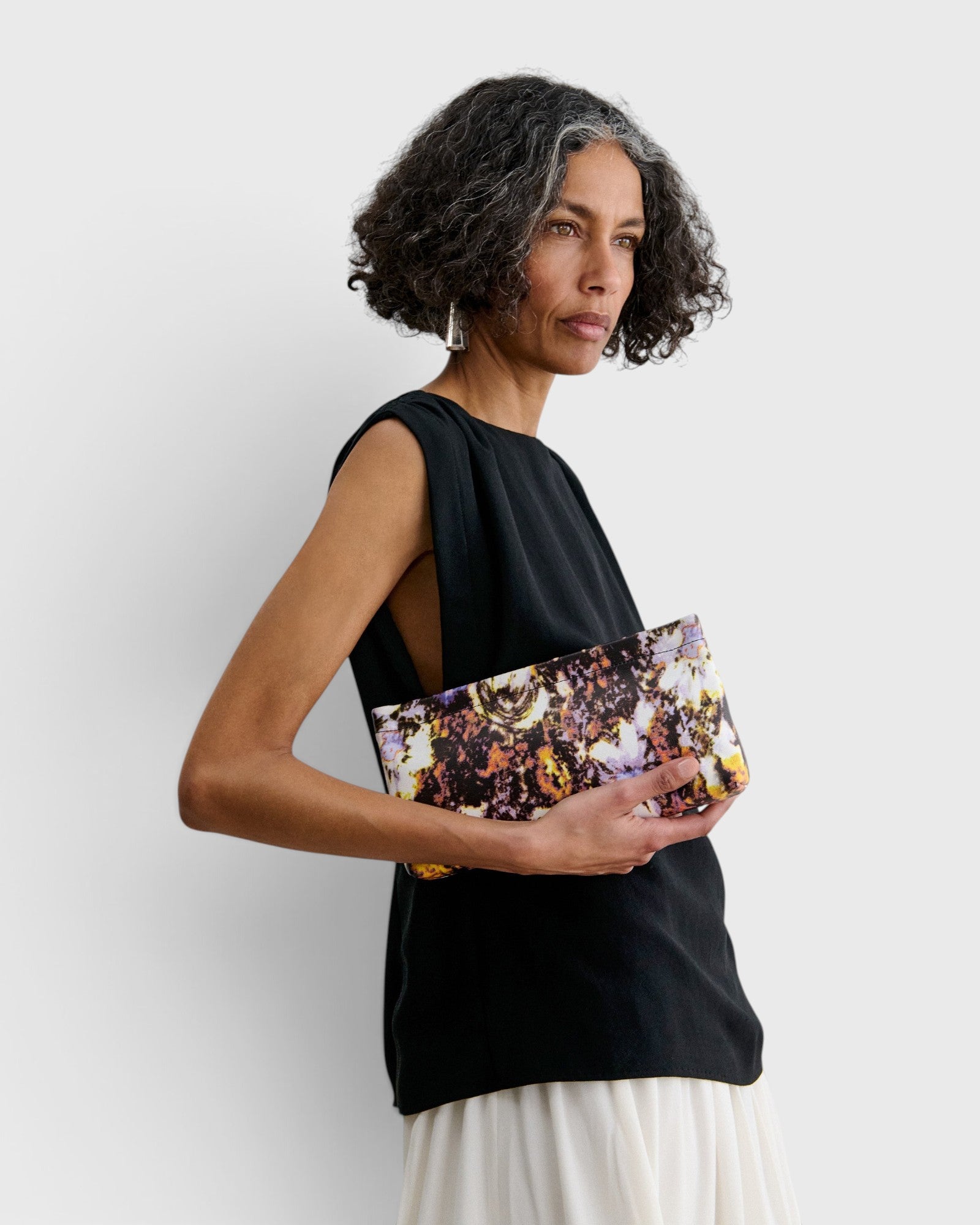JONES + CO small envelope clutch with abstract floral watercolor print and hinge closure held by a woman