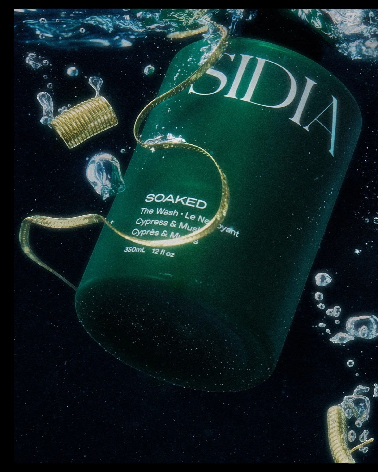 JONES + CO The SOAKED Wash, a champagne-hued hand and body cleanser with cypress and musk notes, submerged in water.