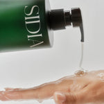 JONES + CO The SOAKED Wash, a champagne-hued hand and body cleanser with avocado butter and shea butter, being dispensed onto a soapy hand.