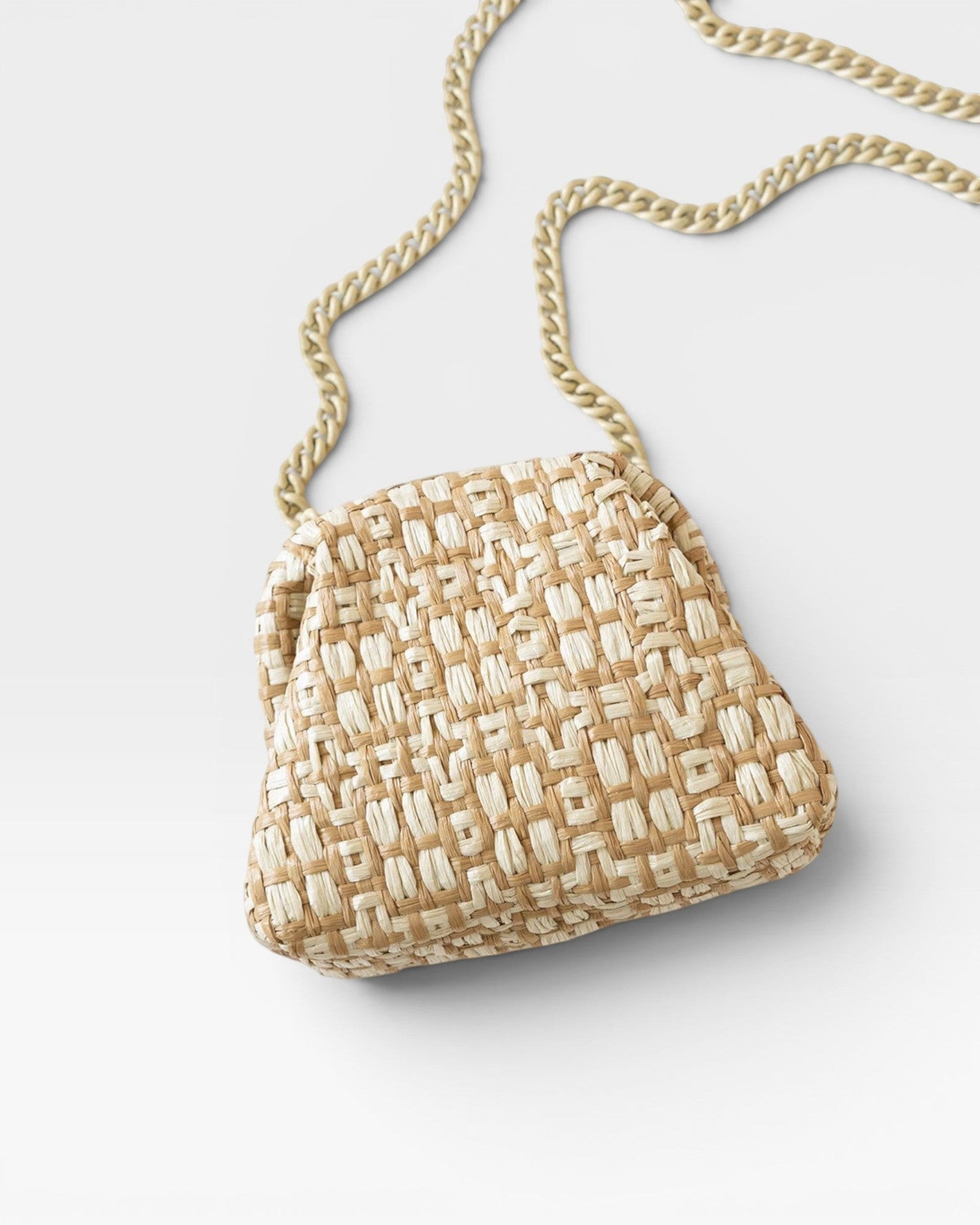 JONES + CO Stella Clutch in natural woven straw with a gold chain strap.
