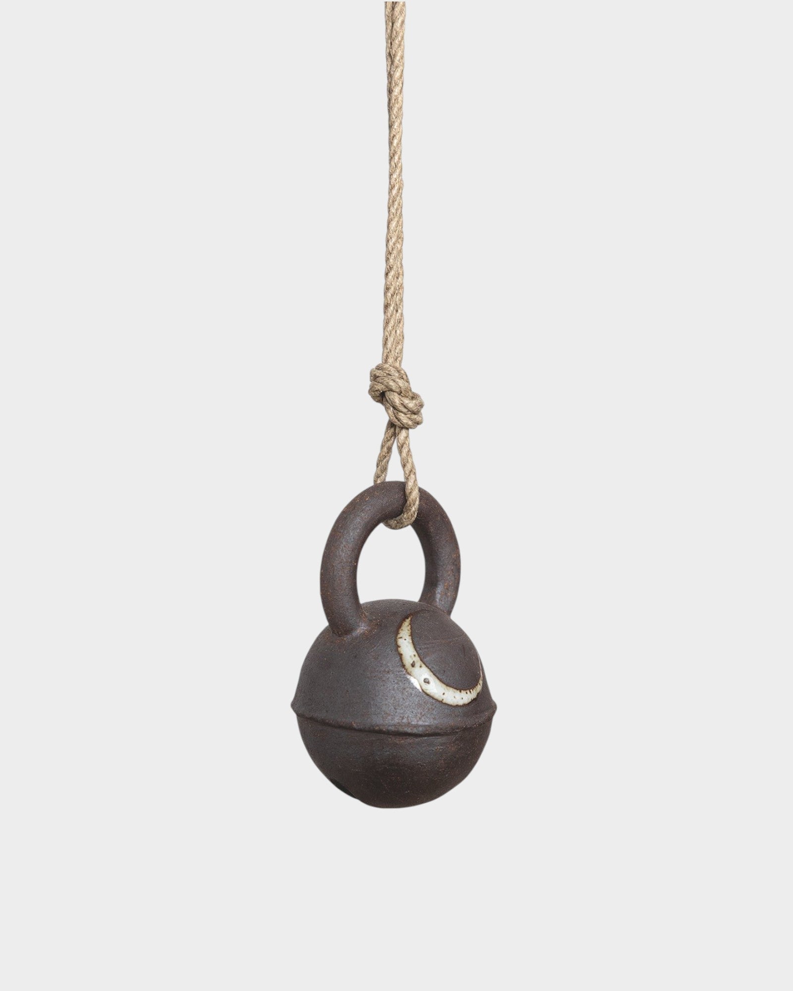 JONES + CO round extra dark stoneware jingle bell with hand-painted yellow crescent moon on a hemp rope hanger.