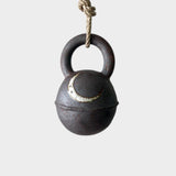 JONES + CO round extra dark stoneware jingle bell featuring a hand-painted crescent moon, hanging on a hemp rope.