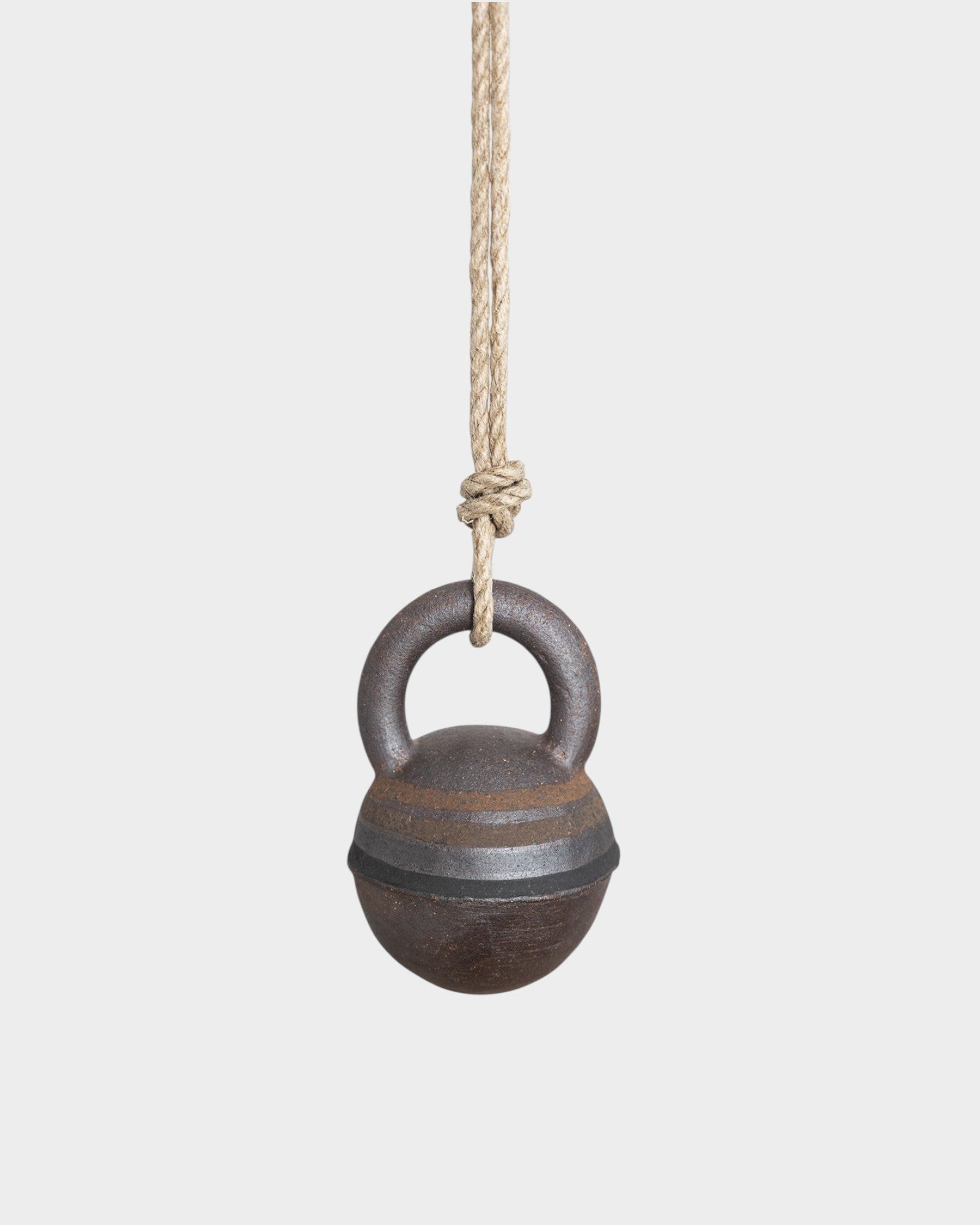 JONES + CO XS stoneware jingle bell with hand-painted black and brown rings, hanging from a natural hemp rope.