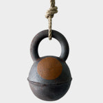 JONES + CO extra dark stoneware jingle bell with a hand-painted yellow crescent moon design on hemp rope.