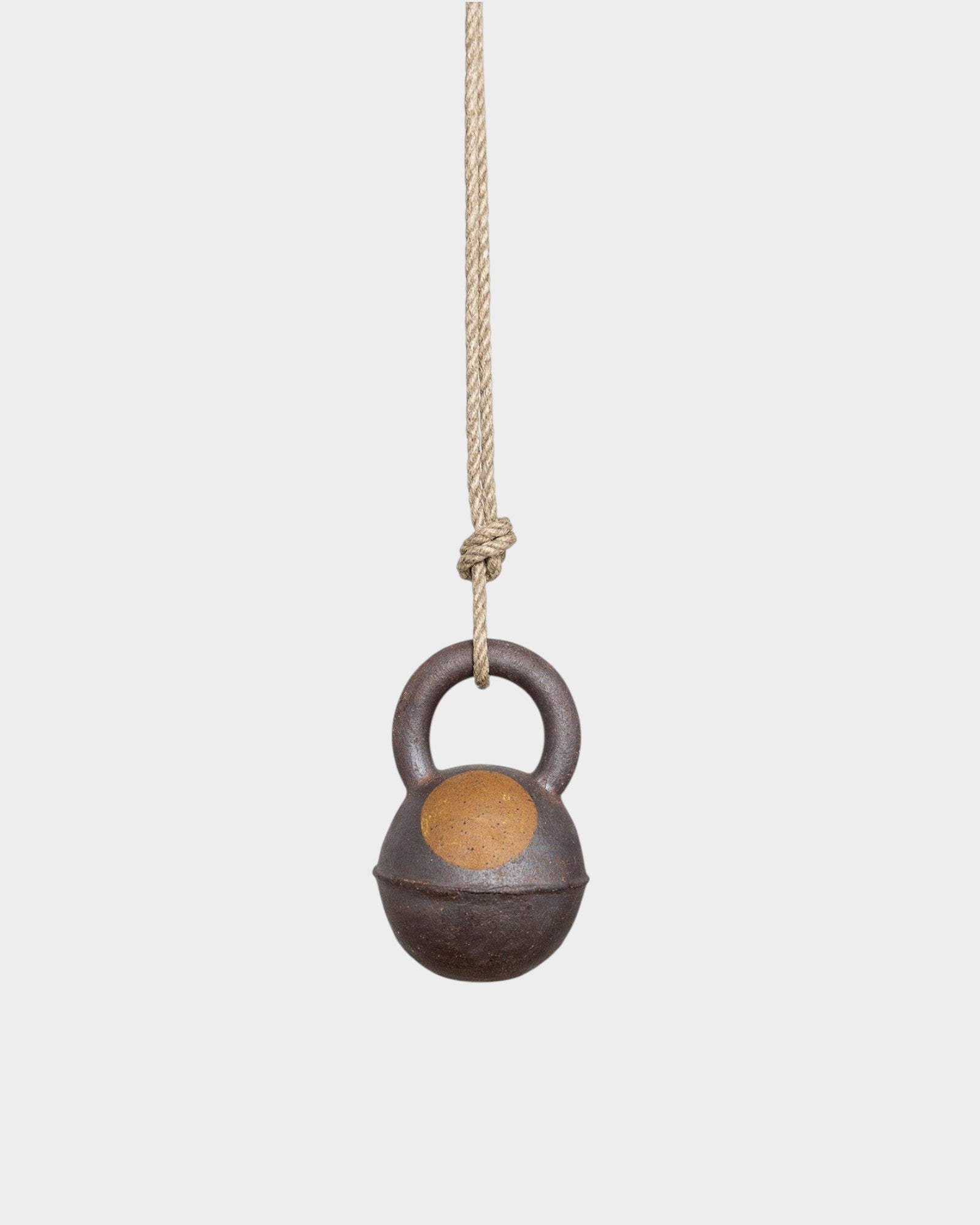 JONES + CO round stoneware jingle bell in extra dark finish with a yellow sun design, hanging from a hemp rope.