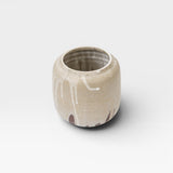 JONES + CO handcrafted stoneware pot with smooth cylindrical shape, beige finish, and white glaze drips. Modern artisan style.