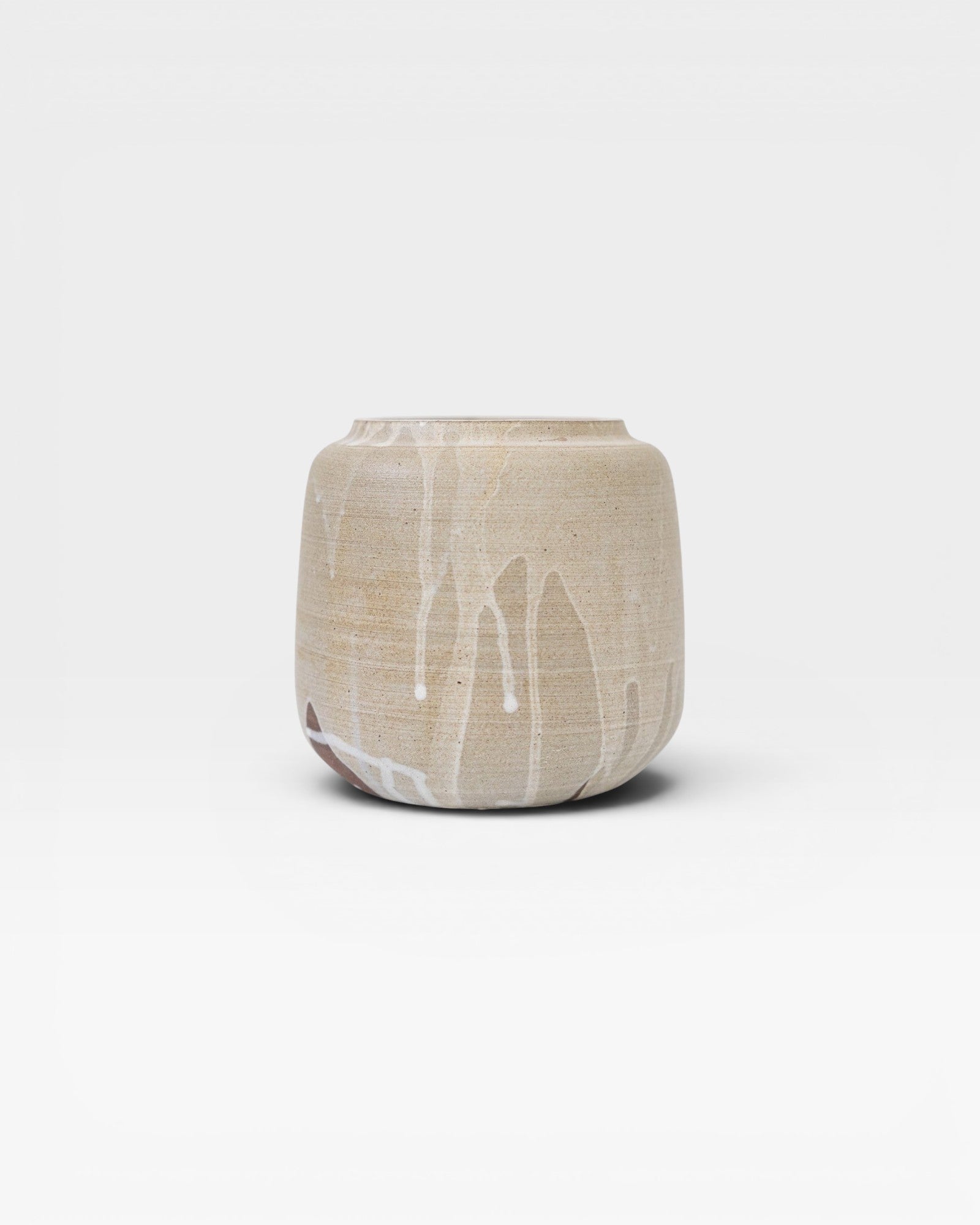 JONES + CO handcrafted beige stoneware pot with white glaze drips, smooth cylindrical shape, modern artisan style.