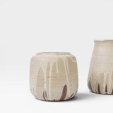 JONES + CO handcrafted stoneware pot with beige finish and white glaze drips. Cylindrical shape, modern artisan style.