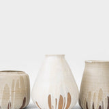JONES + CO handcrafted beige stoneware pot with white glaze drips and smooth cylindrical shape.
