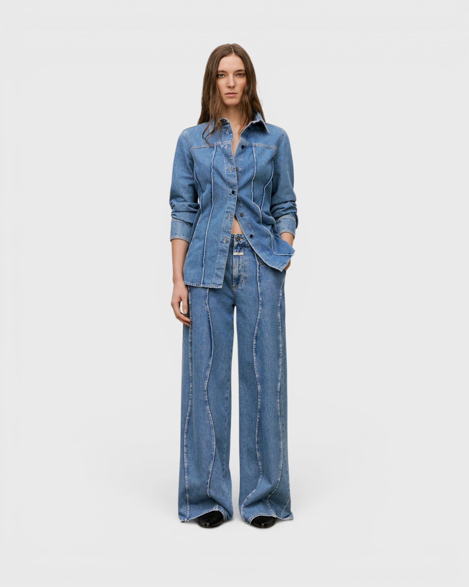 JONES + CO Tali-X mid blue denim jeans with high waist, wide leg, and signature curved seaming on a model
