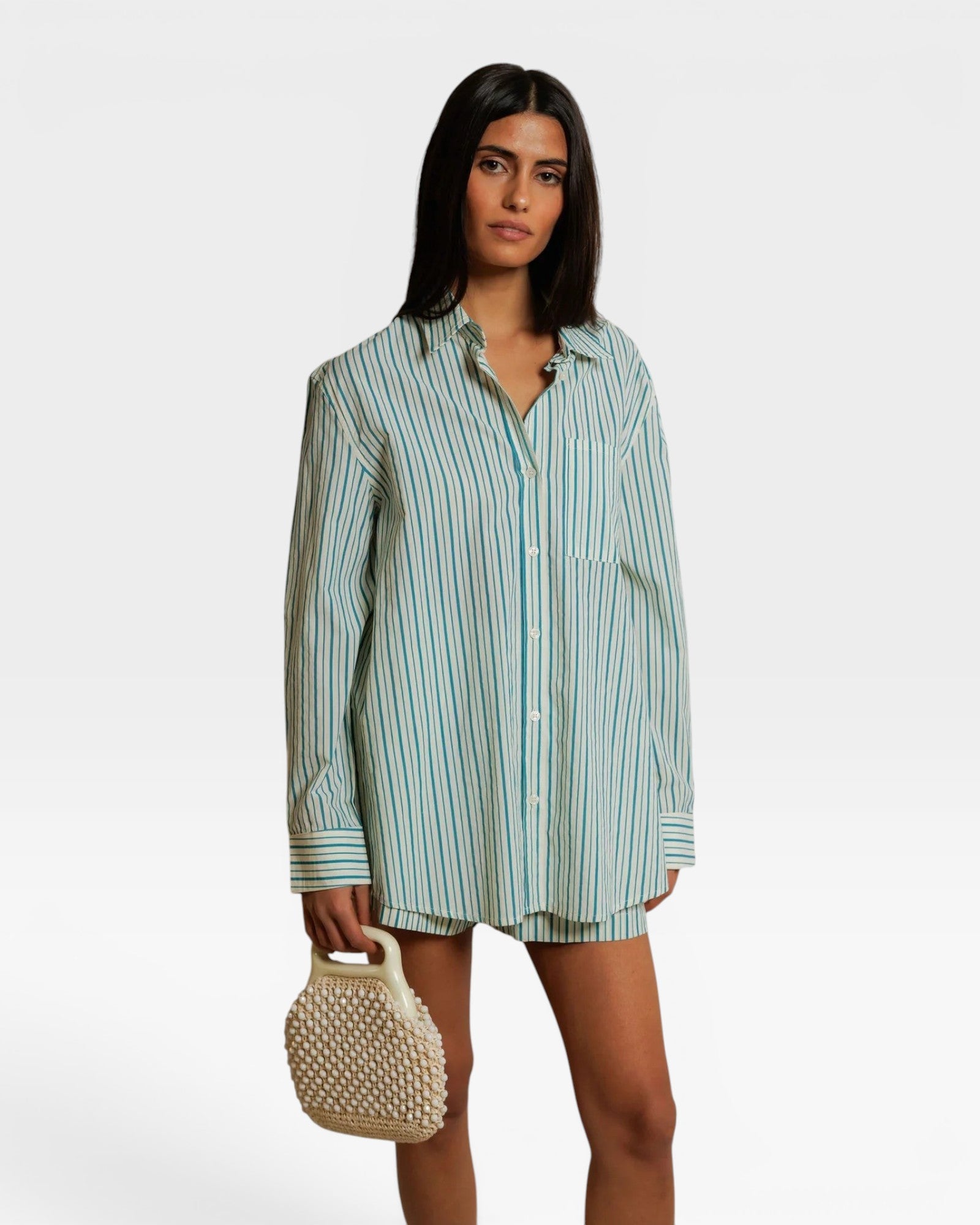 JONES + CO Avalon teal blue and sugar stripe cotton poplin button-down shirt worn by a model with a beaded bag