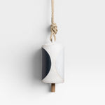 JONES + CO Thrown Bell - Domino Indigo ceramic bell with indigo and white half-moon design, hanging from rope.