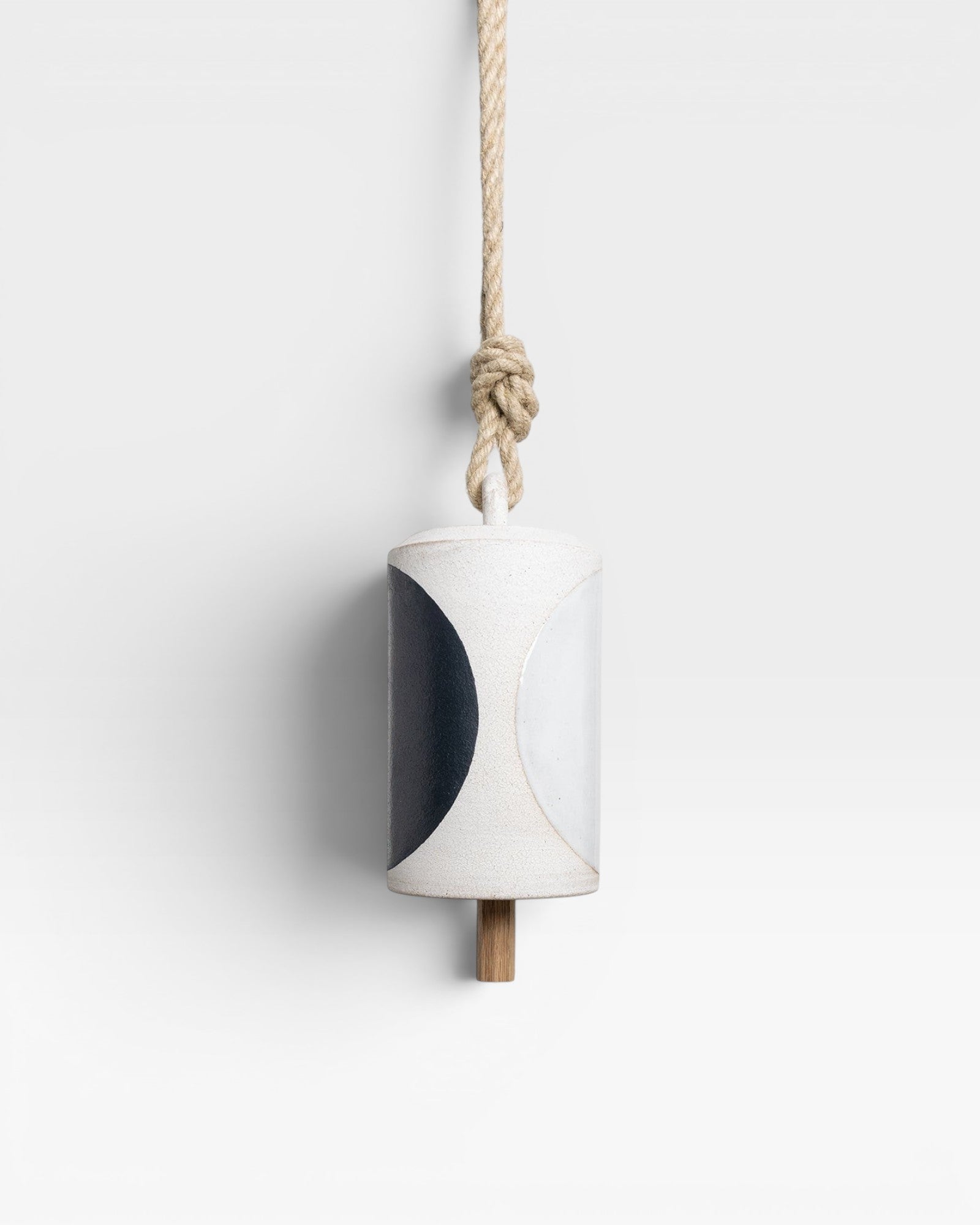JONES + CO Thrown Bell - Domino Indigo ceramic bell with indigo and white half-moon design, hanging from rope.