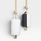 JONES + CO Thrown Bell - Domino Indigo, two ceramic bells hanging from rope. One bell is white with a large white oval detail. The other is half black, half white.