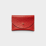 JONES + CO tomato red leather cardholder with a solid brass fastener, front view on a light grey background.