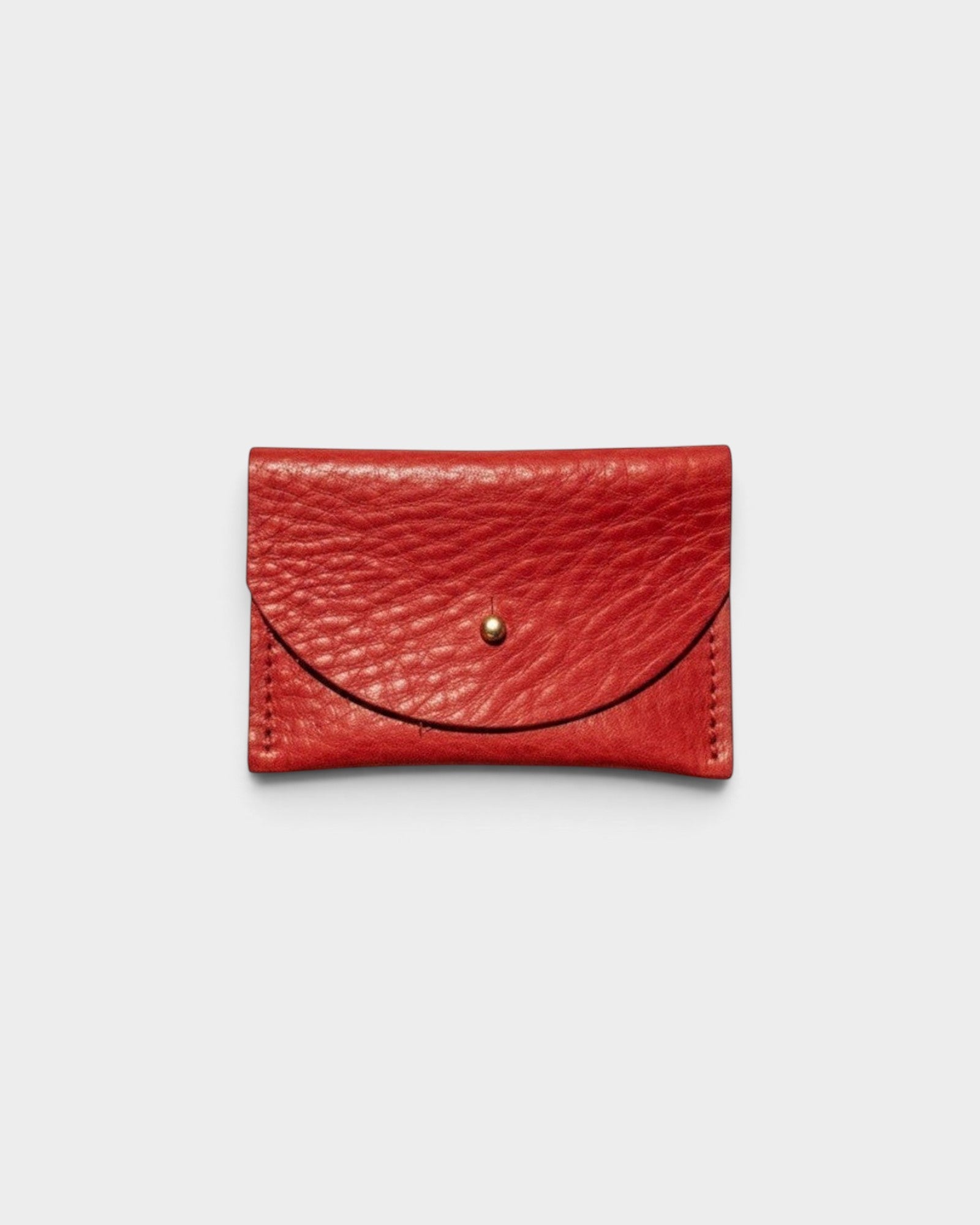JONES + CO tomato red leather cardholder with a solid brass fastener, front view on a light grey background.