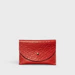 JONES + CO tomato red leather cardholder with a solid brass fastener, front view on a light grey background.