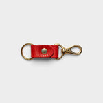 JONES + CO tomato red leather keychain with solid brass keyring and clip hardware on a neutral background.
