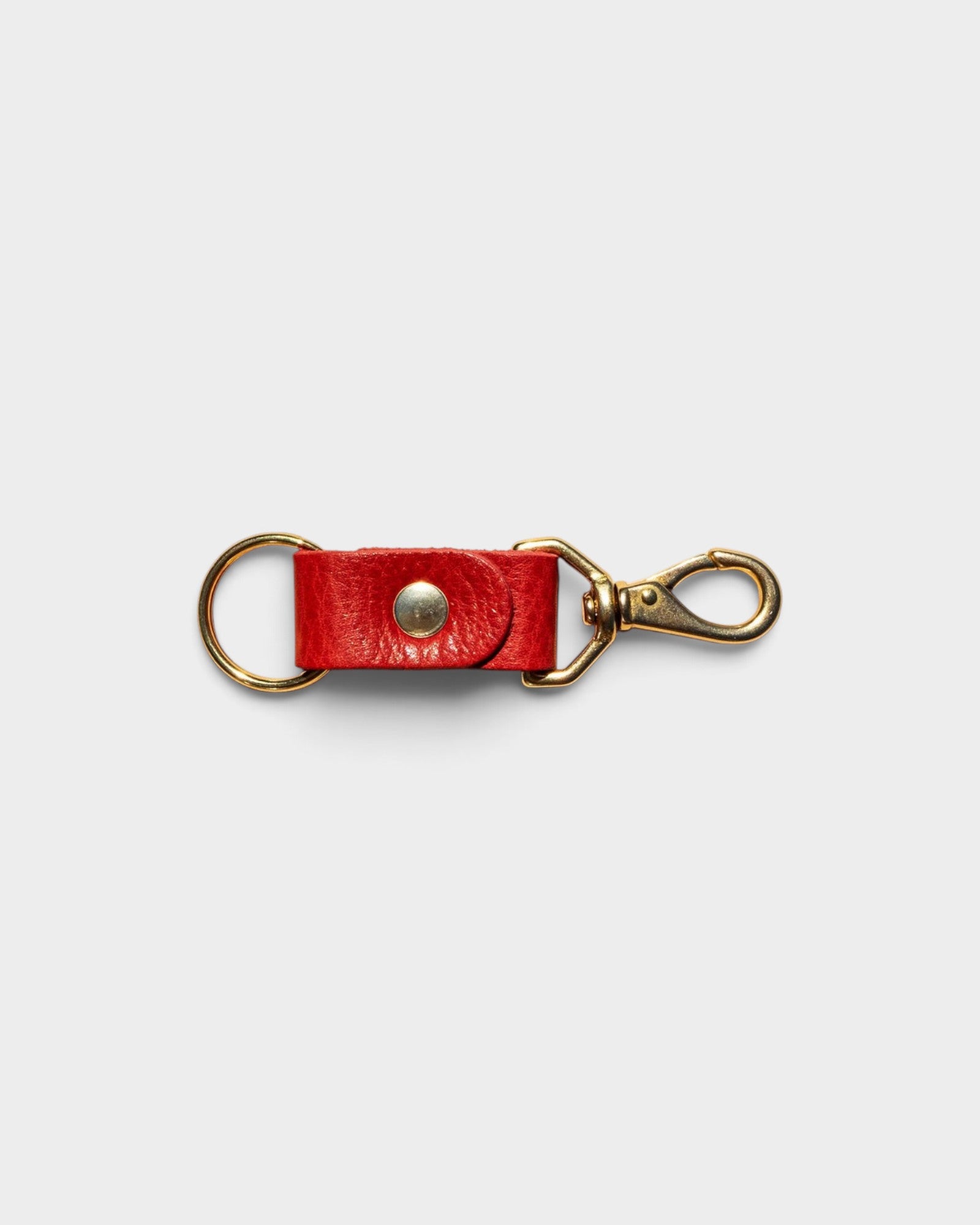 JONES + CO tomato red leather keychain with solid brass keyring and clip hardware on a neutral background.