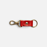 JONES + CO tomato red leather keychain with gold-tone metal hardware and a secure snap button closure.