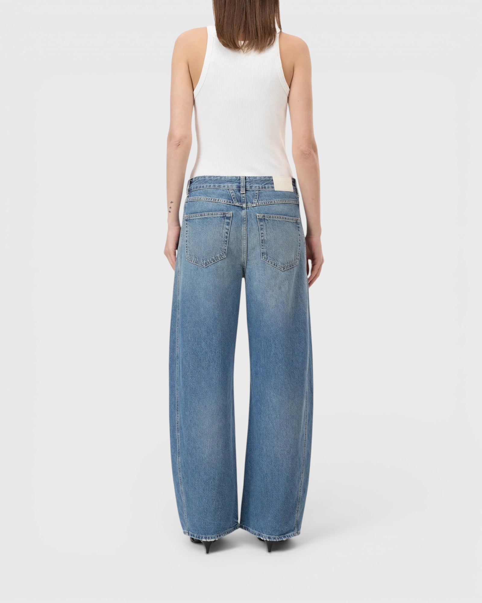JONES + CO Tori-X barrel jeans in mid blue denim with offset side seams and back pockets, back view on a model.