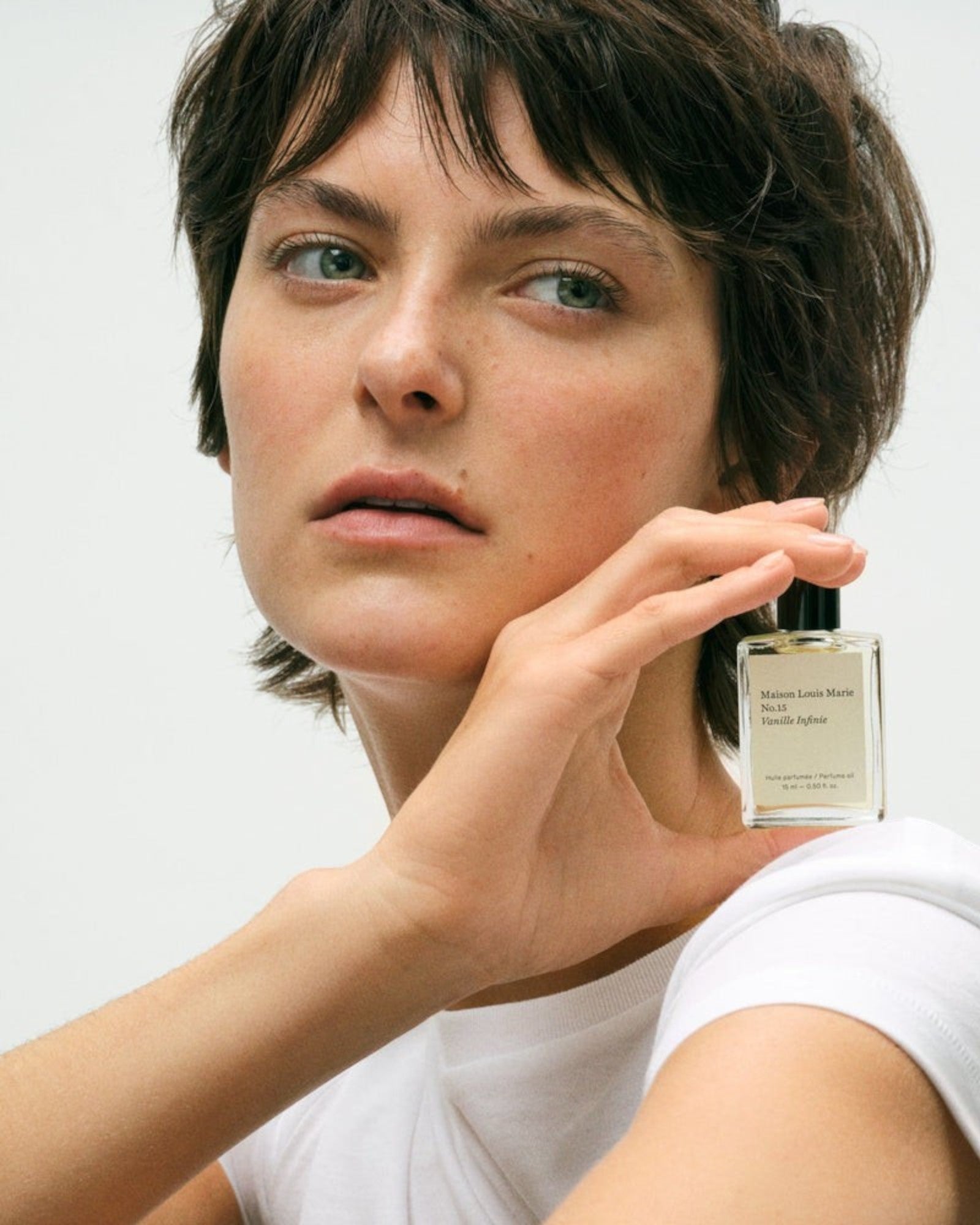 JONES + CO No.15 Vanille Infinie perfume oil bottle held by a woman with short brown hair and green eyes.