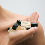 JONES + CO No.15 Vanille Infinie mini perfume oil bottles with black caps held in a hand.