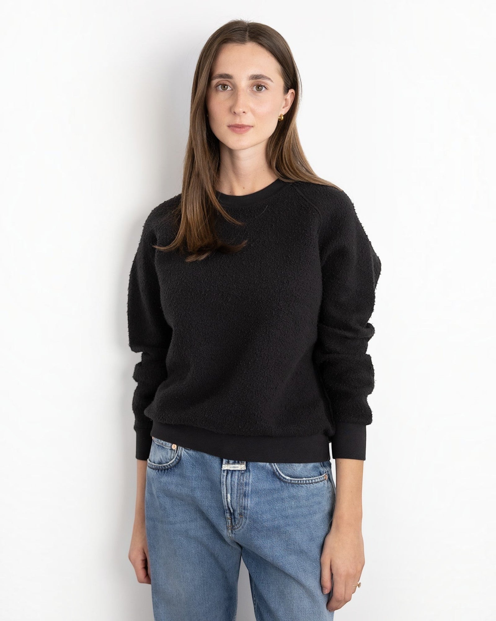 Woman wearing a JONES + CO vintage black textured crewneck sweatshirt with ribbed cuffs and hem