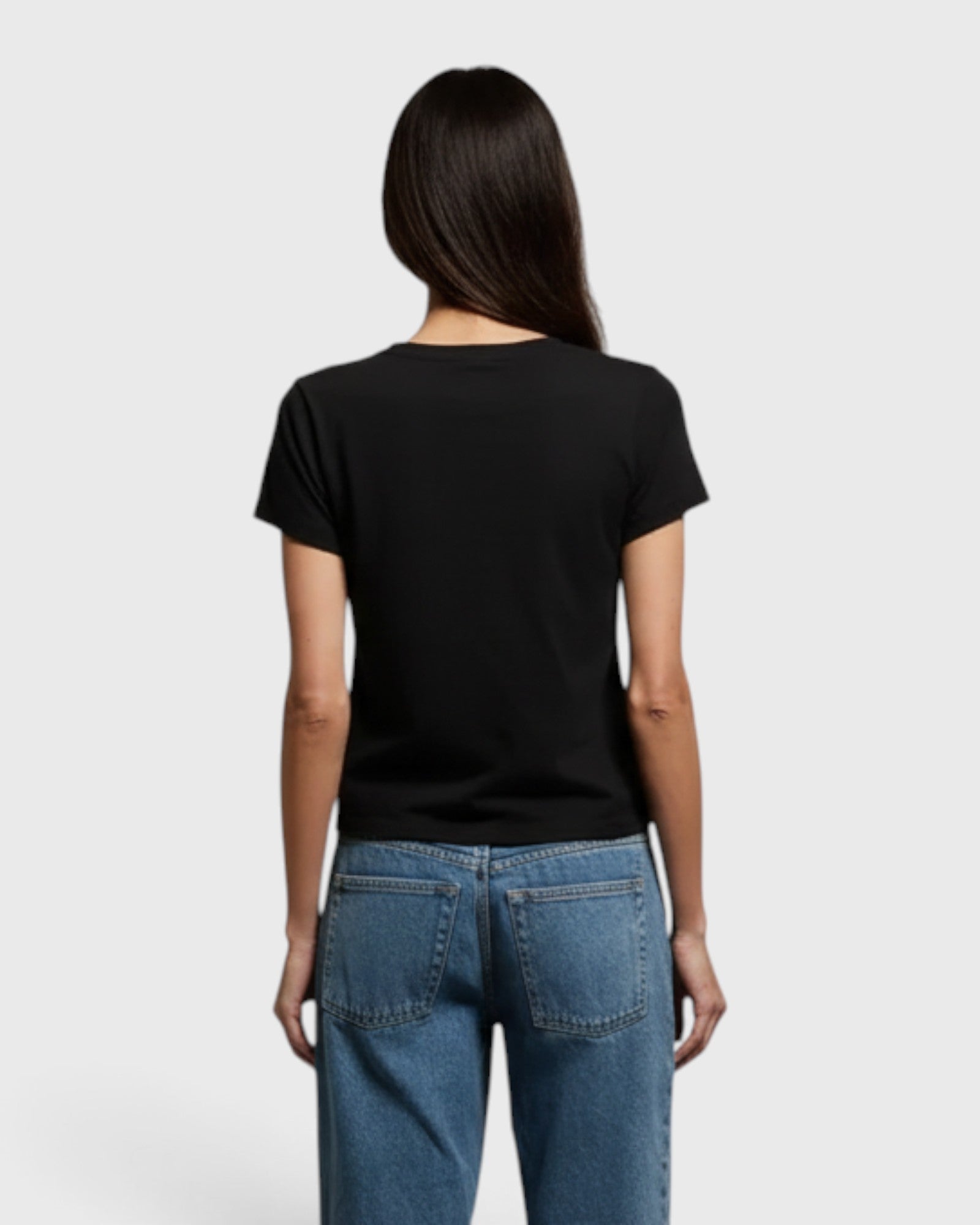 Back view of a model wearing a JONES + CO vintage black recycled cotton V-neck t-shirt with blue jeans.