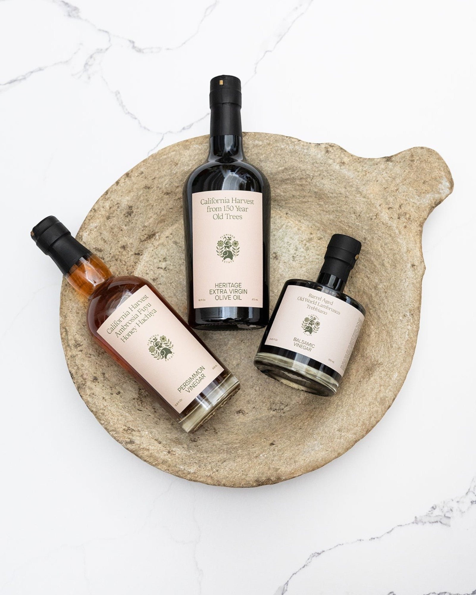 JONES + CO Vintage Marble Parat Bowl with three bottles of olive oil and vinegar.