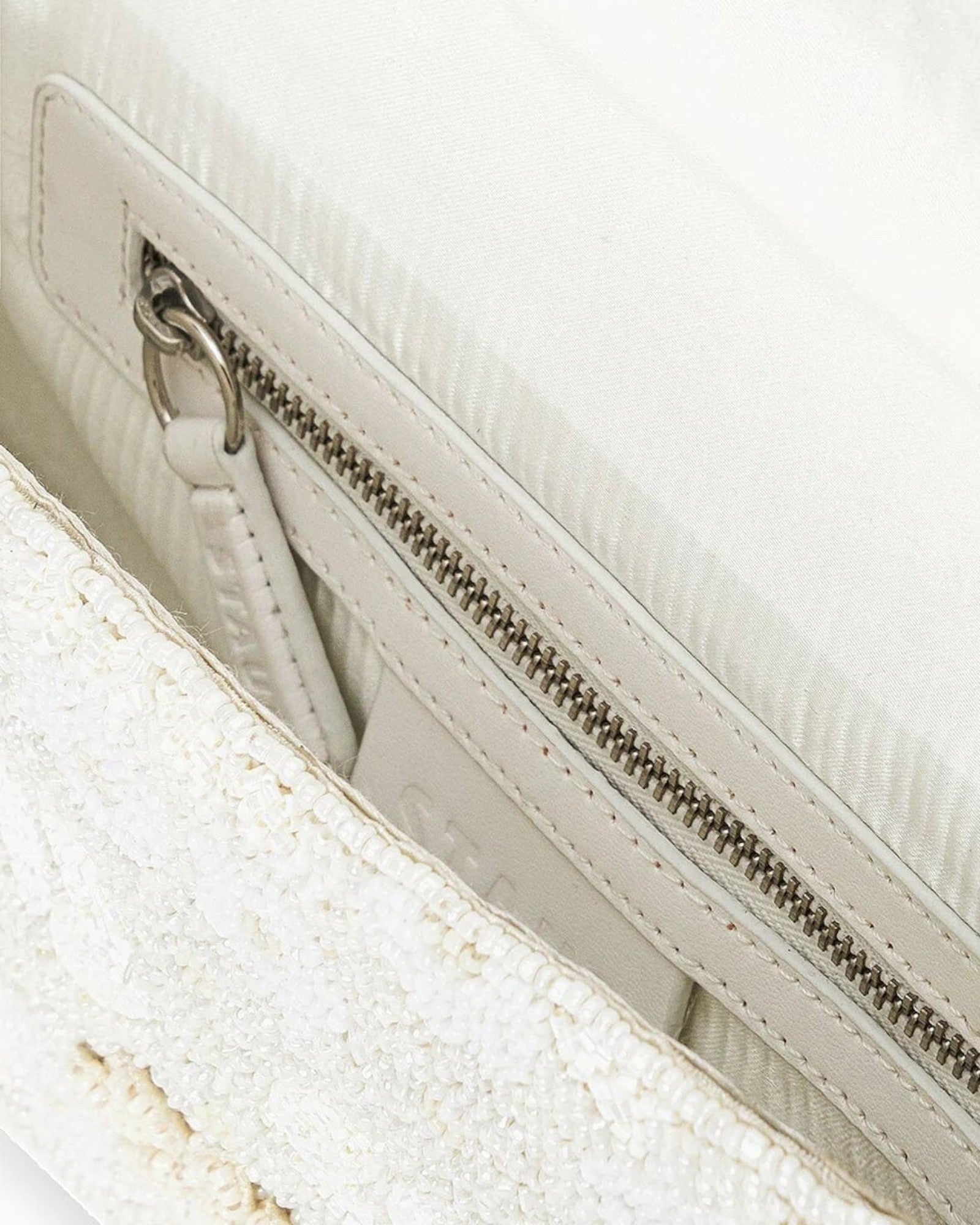 JONES + CO white beaded shoulder bag with 3D floral embellishments and vegan leather trim. Features inner zip pocket.