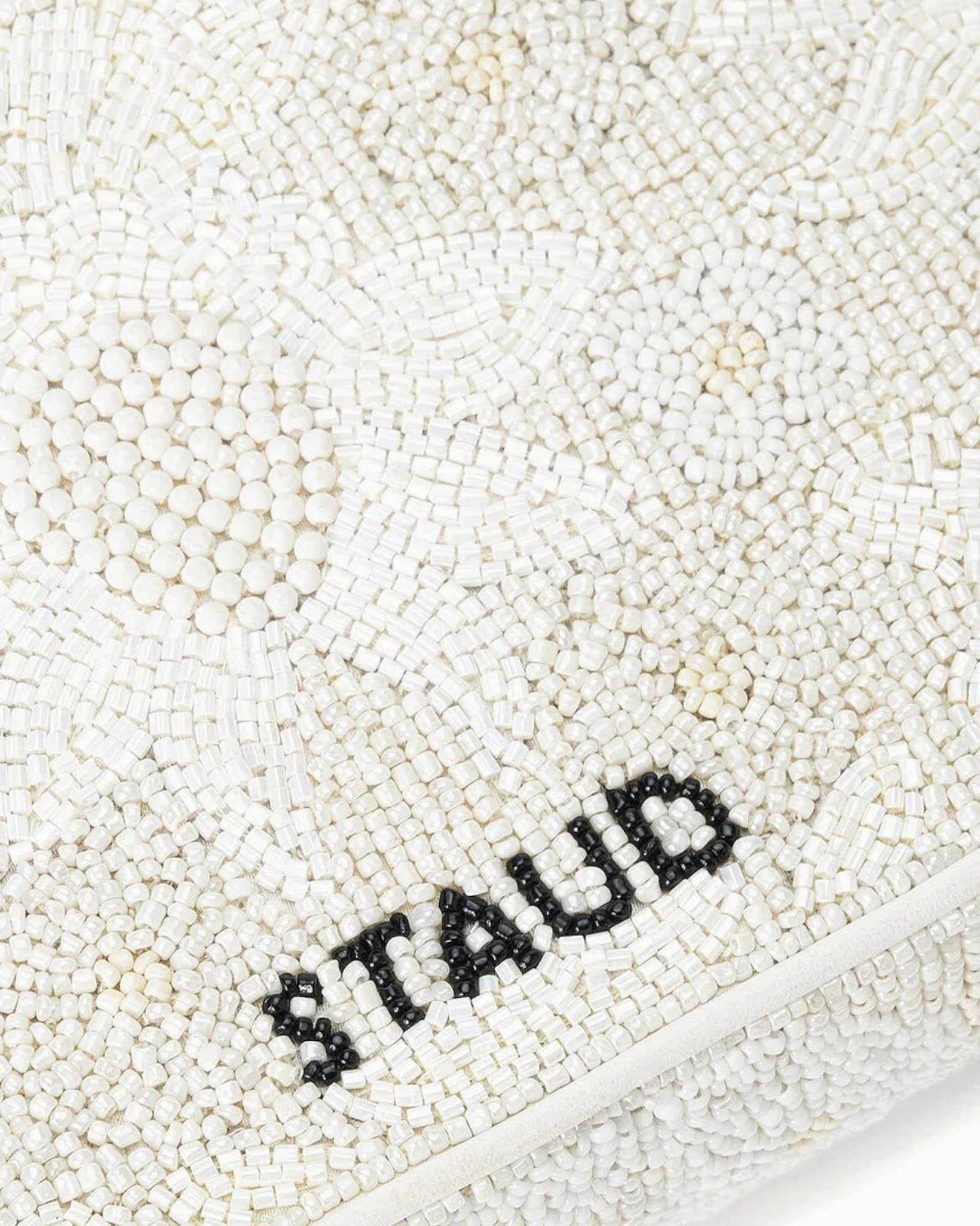 JONES + CO white beaded shoulder bag with "STAUD" logo in black beads. Features 3D flowers and vegan leather piping.
